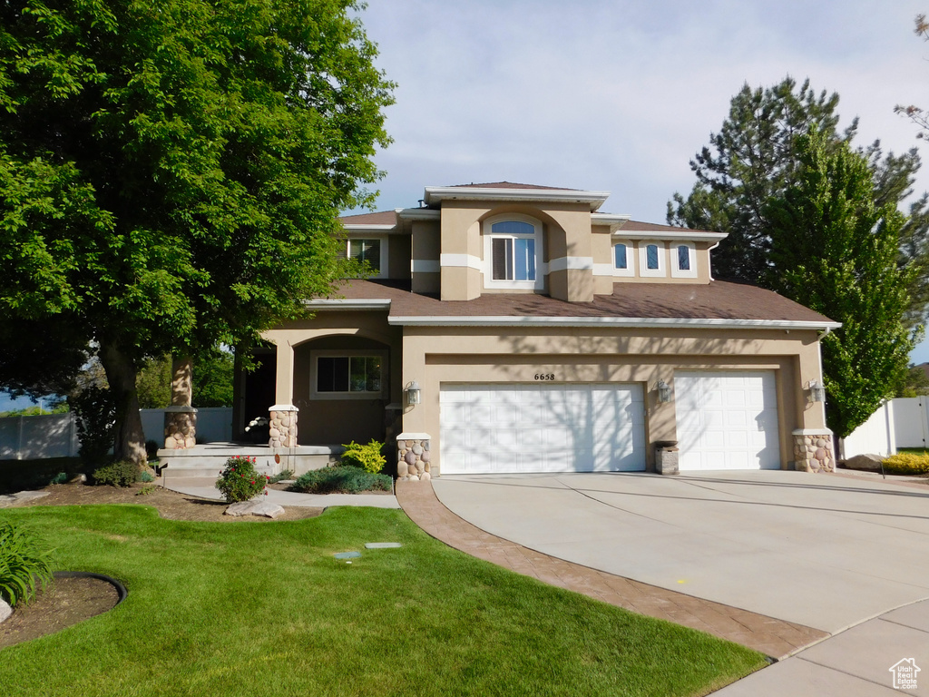 View of front of house featuring stucco siding, concrete driveway, stone siding, and an attached garage