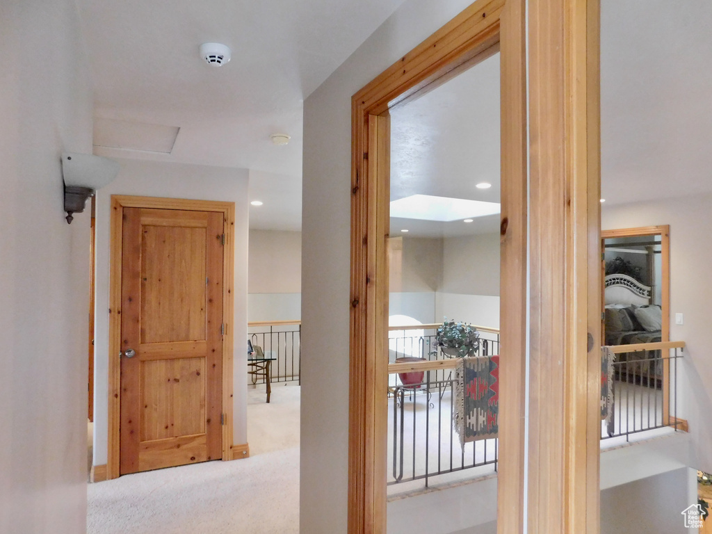Corridor with an upstairs landing, attic access, carpet floors, and recessed lighting