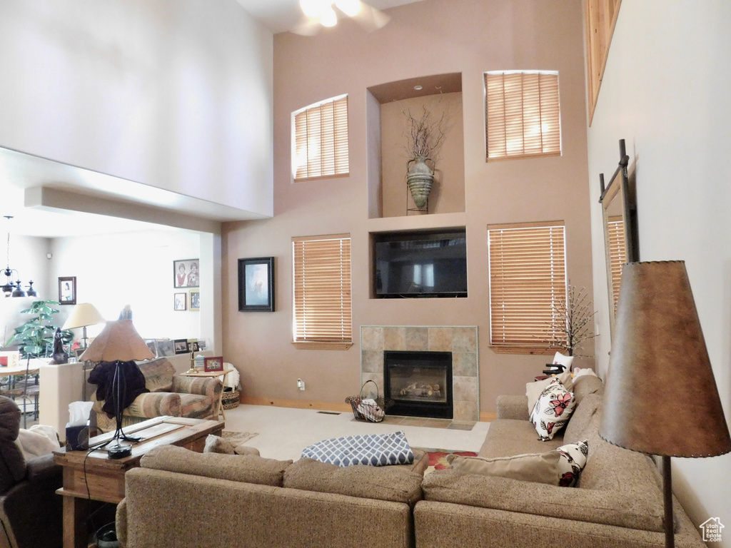 Living room featuring a towering ceiling, a fireplace, carpet floors, and ceiling fan