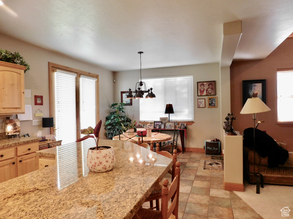 Kitchen featuring light brown cabinetry, a kitchen bar, light stone countertops, and baseboards