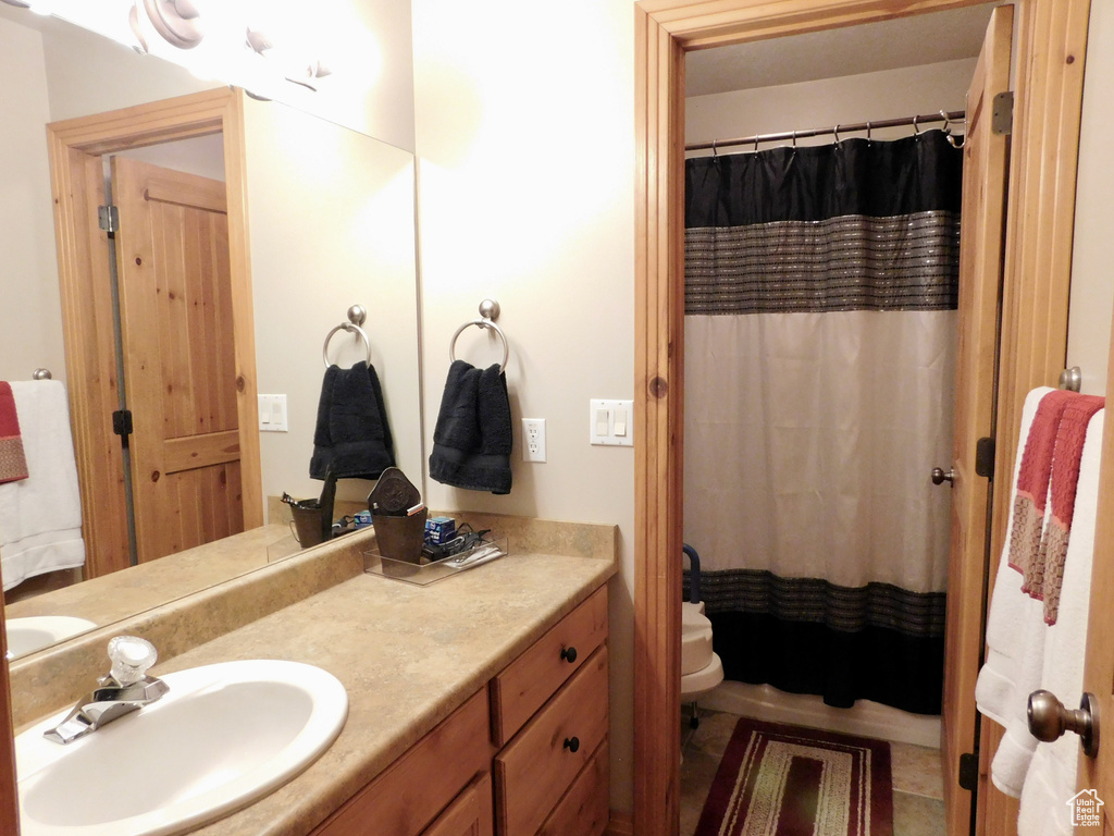 Bathroom featuring vanity, toilet, and curtained shower