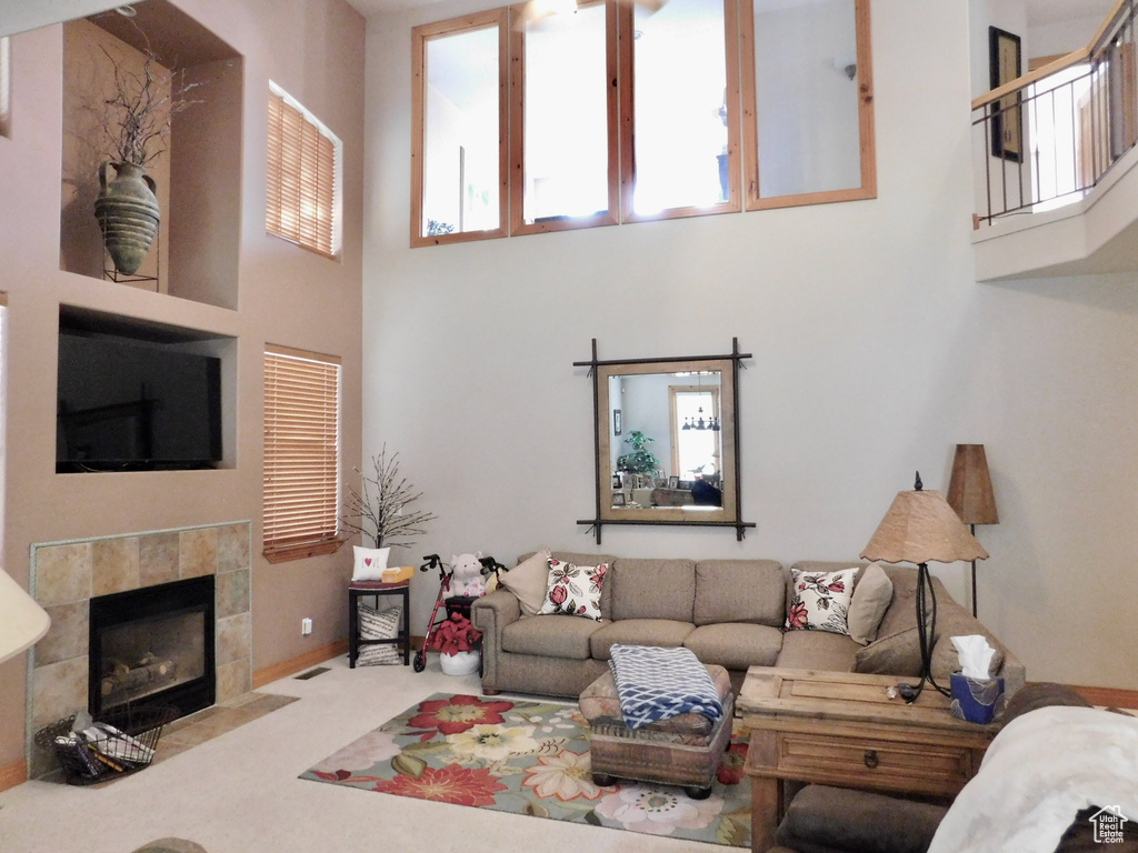 Living room with a towering ceiling, a tile fireplace, and carpet flooring