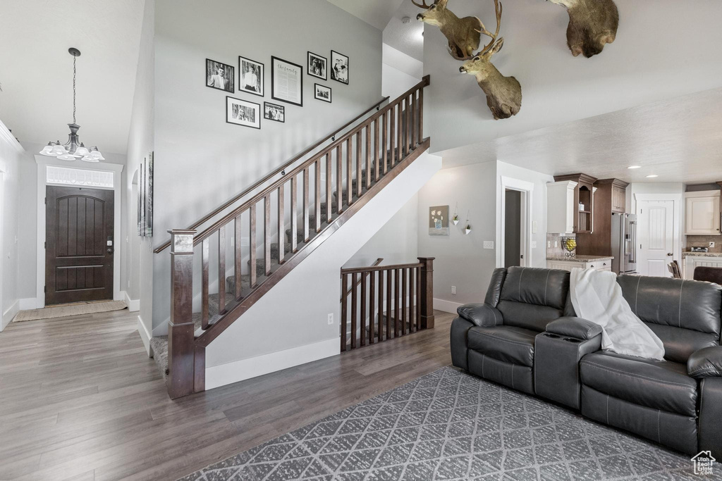 Living room with baseboards, wood finished floors, a chandelier, recessed lighting, and stairs