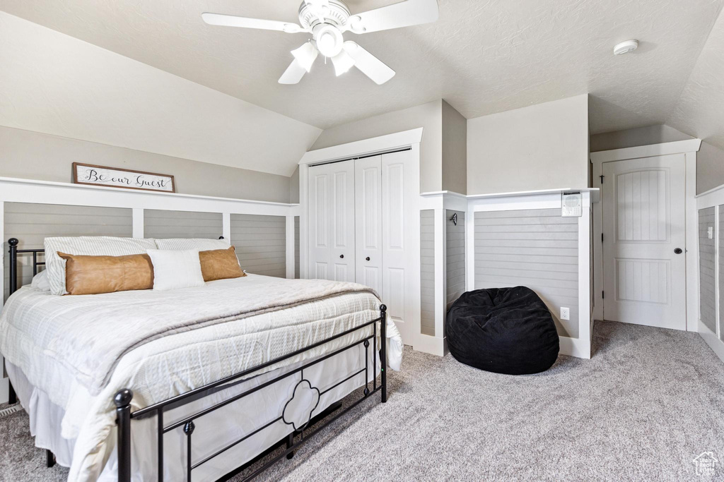 Carpeted bedroom featuring a closet, vaulted ceiling, a ceiling fan, and baseboards