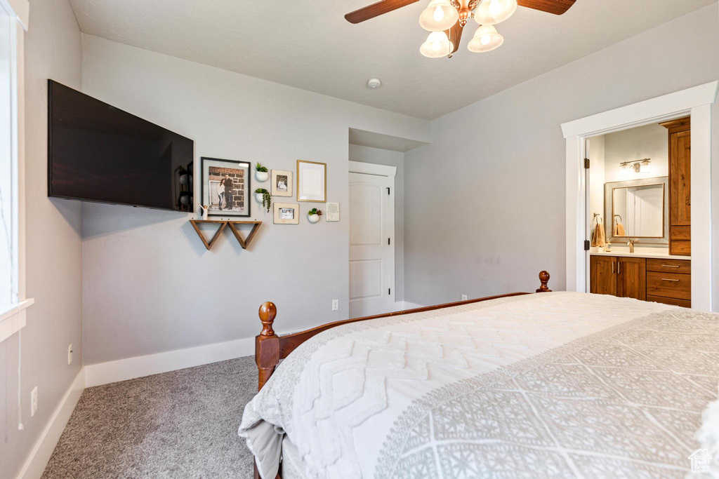 Carpeted bedroom with baseboards, ensuite bathroom, and a ceiling fan