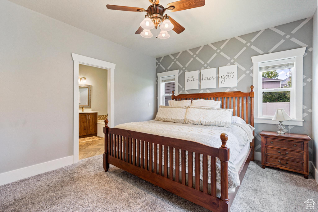 Carpeted bedroom with baseboards, ensuite bath, and a ceiling fan