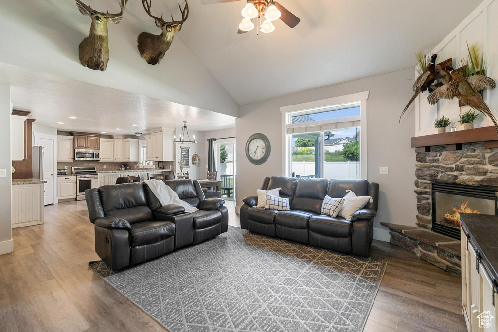 Living room with ceiling fan, light wood finished floors, a fireplace, a chandelier, and recessed lighting