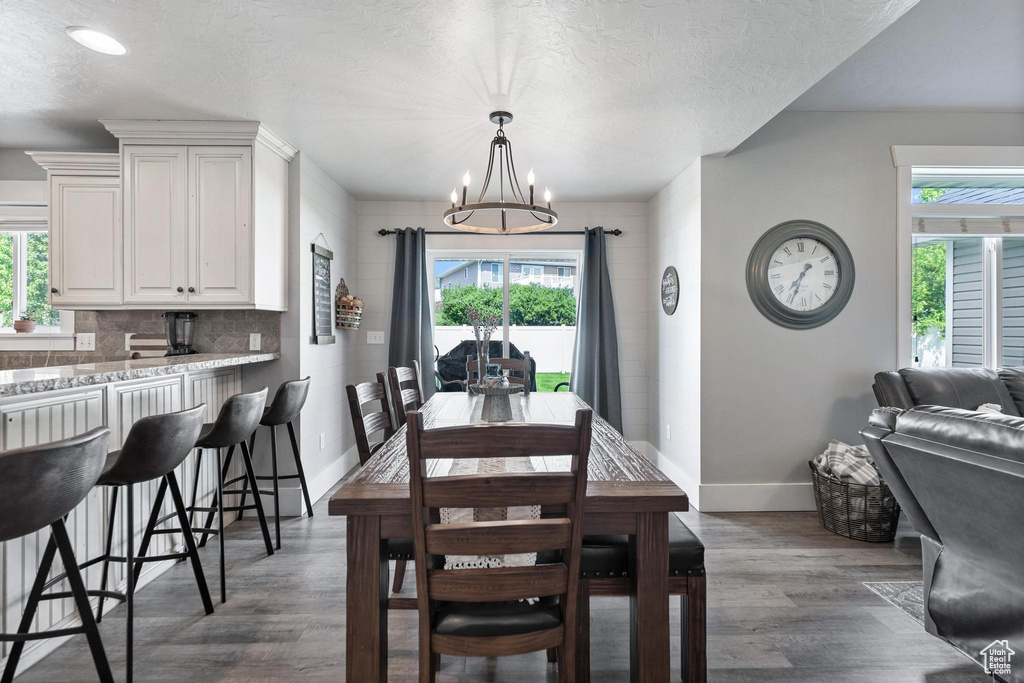 Dining space with a chandelier, healthy amount of natural light, baseboards, dark wood-style floors, and a textured ceiling