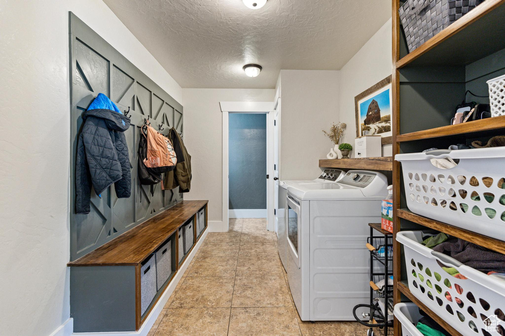 Laundry area featuring separate washer and dryer, a textured ceiling, and baseboards