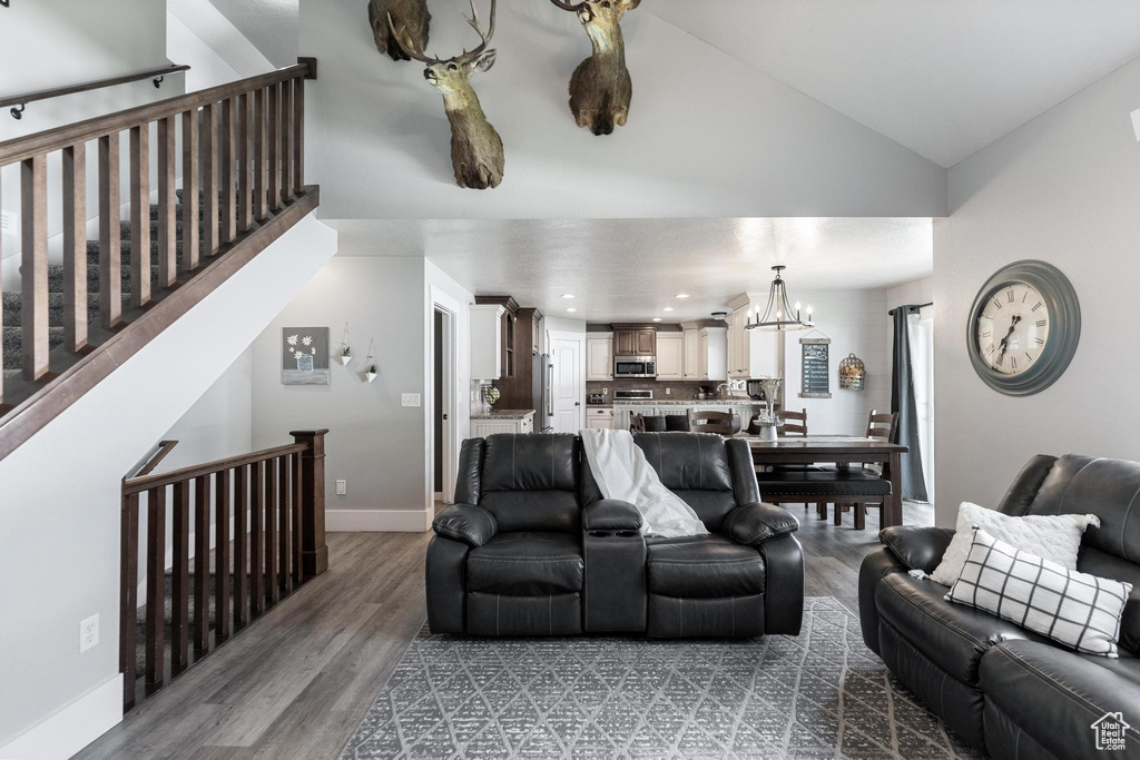 Living area with lofted ceiling, a chandelier, baseboards, wood finished floors, and recessed lighting