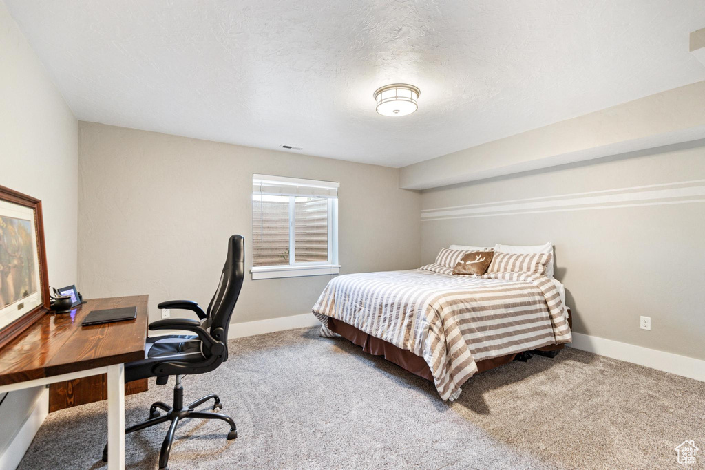 Carpeted bedroom with baseboards and an office area