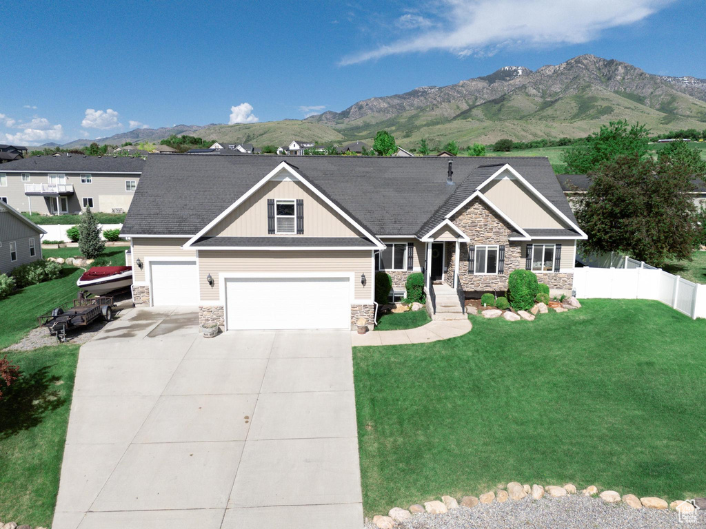 Craftsman inspired home featuring stone siding, a mountain view, concrete driveway, board and batten siding, and a garage