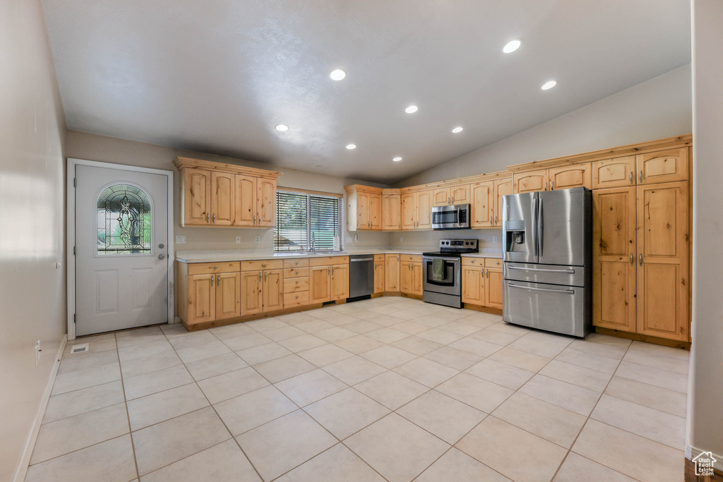 Kitchen featuring stainless steel appliances, light countertops, vaulted ceiling, recessed lighting, and light brown cabinets