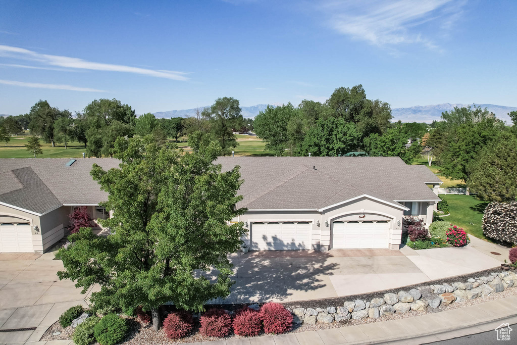 View of front of home with an attached garage, concrete driveway, a mountain view, and a shingled roof