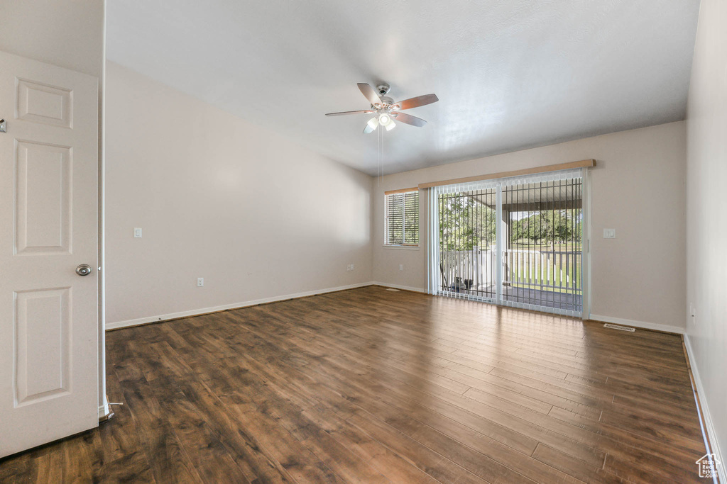 Empty room with a ceiling fan, wood finished floors, and baseboards