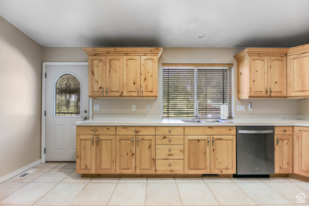 Kitchen featuring stainless steel dishwasher, a sink, and light brown cabinetry