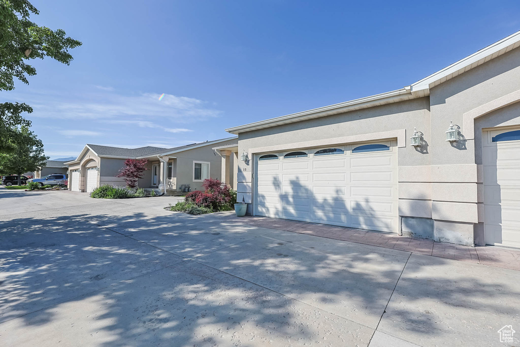 View of front of home featuring driveway, a garage, and stucco siding
