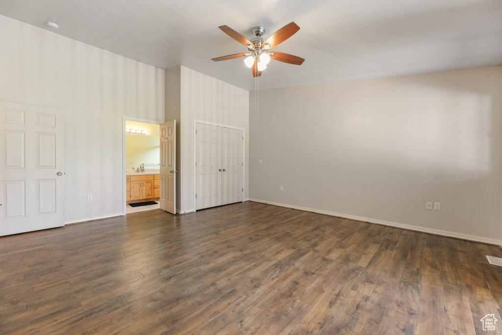 Unfurnished bedroom with dark wood finished floors, baseboards, and connected bathroom