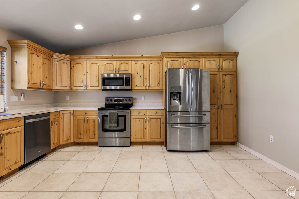 Kitchen with appliances with stainless steel finishes, vaulted ceiling, light countertops, recessed lighting, and light tile patterned floors