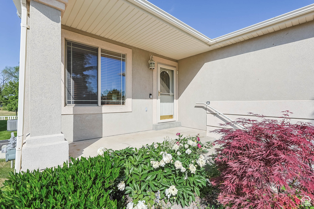 Doorway to property featuring stucco siding and central AC unit