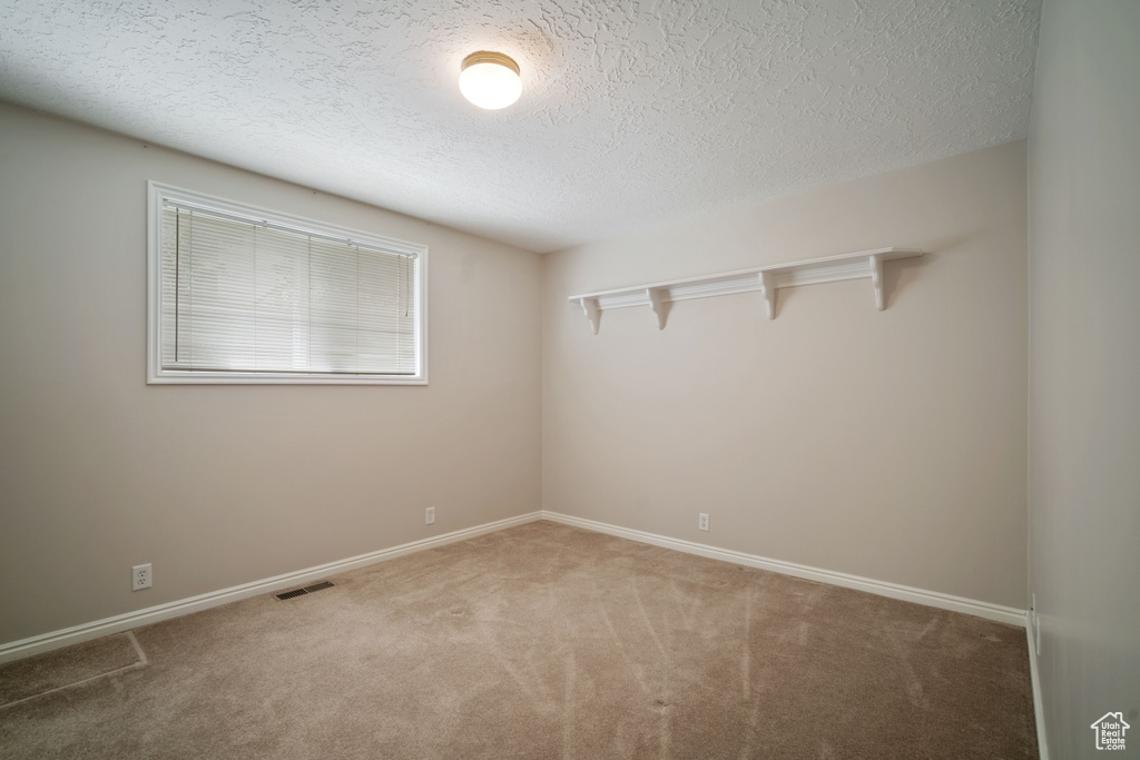 Spare room featuring carpet, a textured ceiling, and baseboards