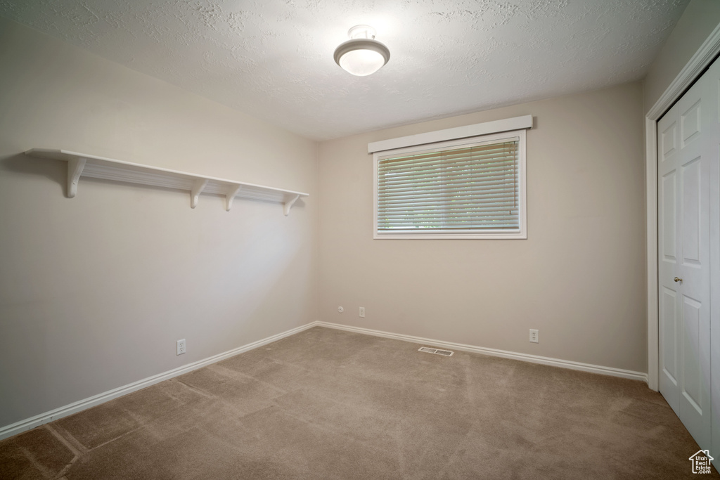 Unfurnished bedroom with carpet floors, a closet, a textured ceiling, and baseboards