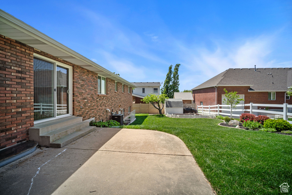 View of yard featuring a patio, entry steps, and central AC unit