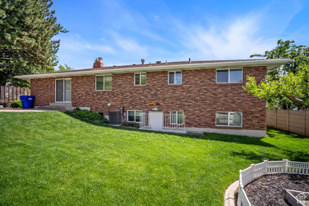 Back of house with a chimney, brick siding, and cooling unit