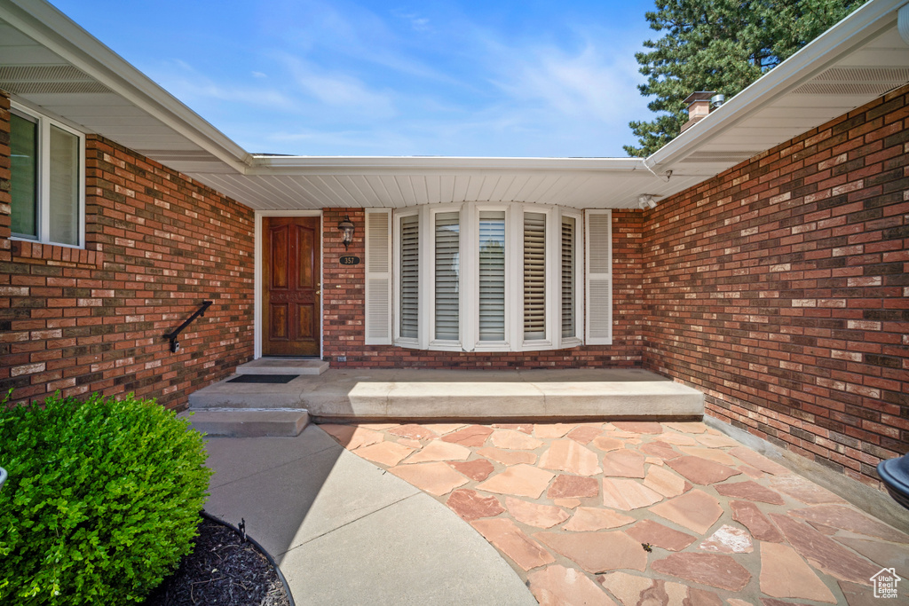 Doorway to property with brick siding and a porch