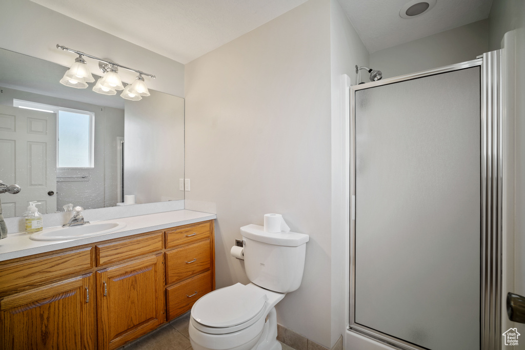 Bathroom with vanity, a shower stall, toilet, and tile patterned floors