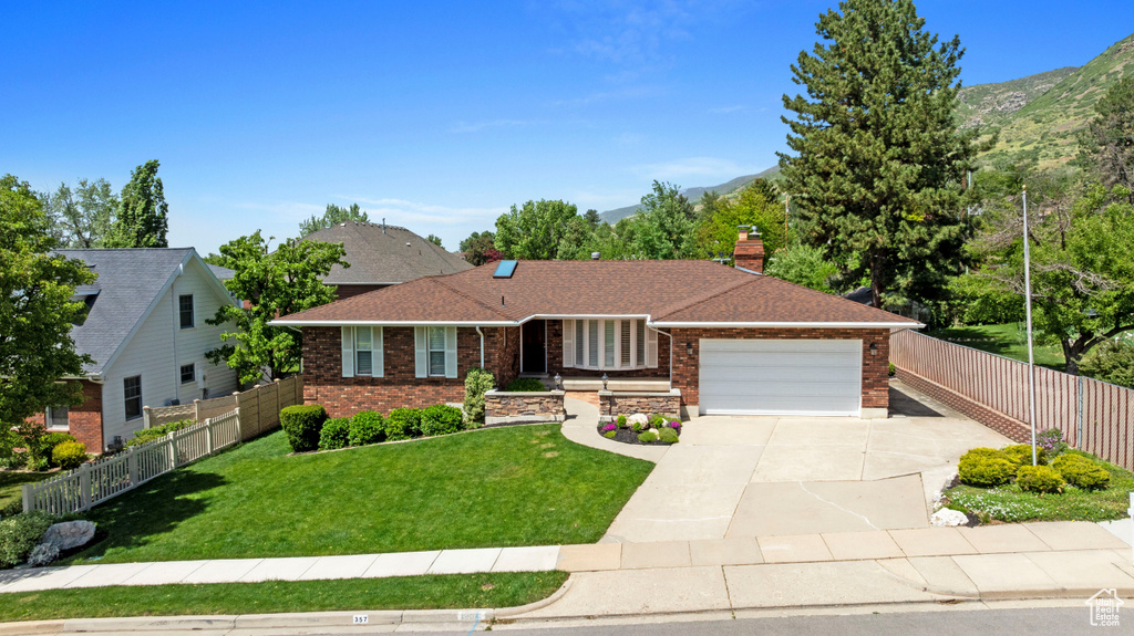 Ranch-style home with brick siding, a garage, driveway, and a mountain view