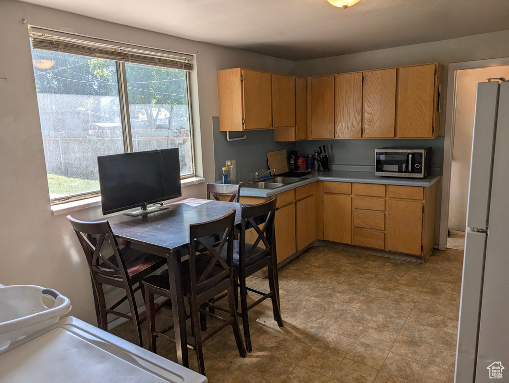 Kitchen with freestanding refrigerator, stainless steel microwave, a sink, and light countertops