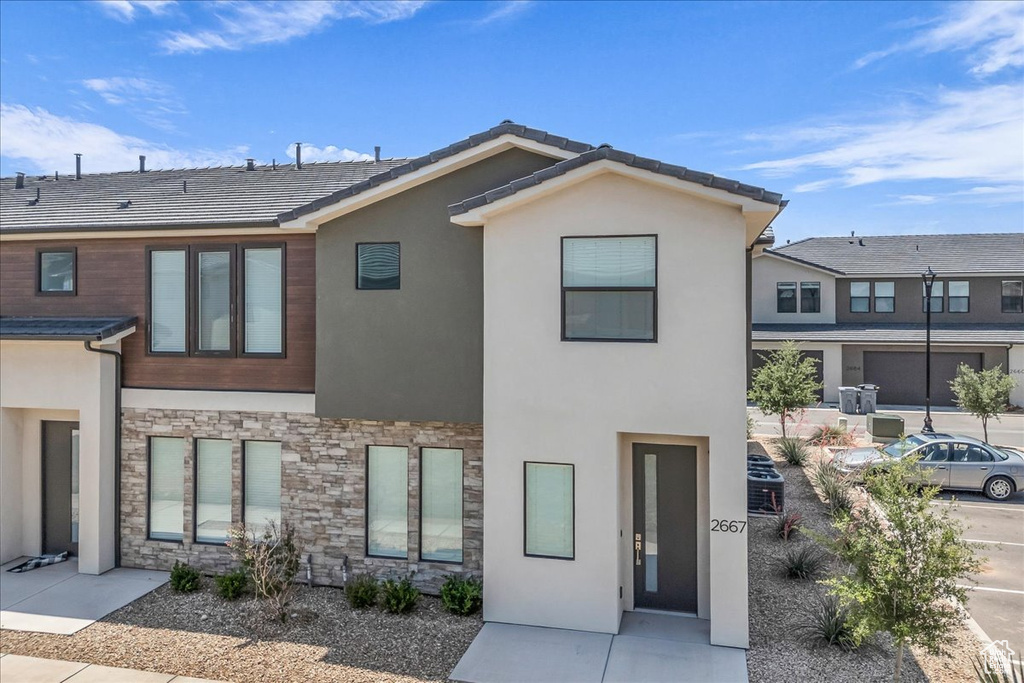 View of front of home featuring stone siding and stucco siding