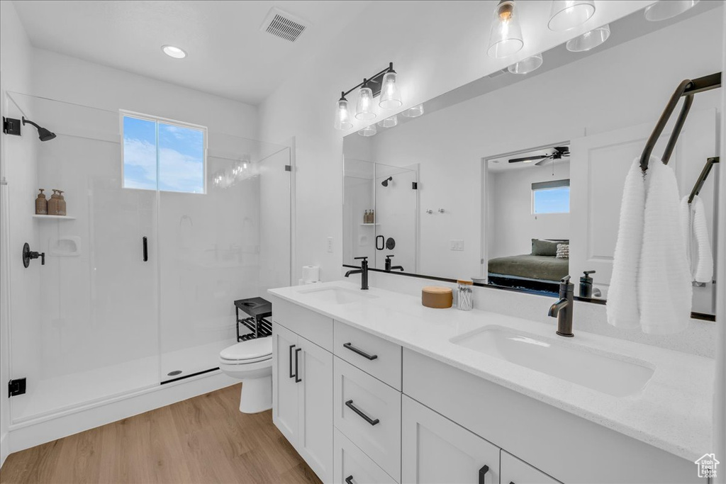 Ensuite bathroom with toilet, a shower stall, double vanity, ceiling fan, and recessed lighting