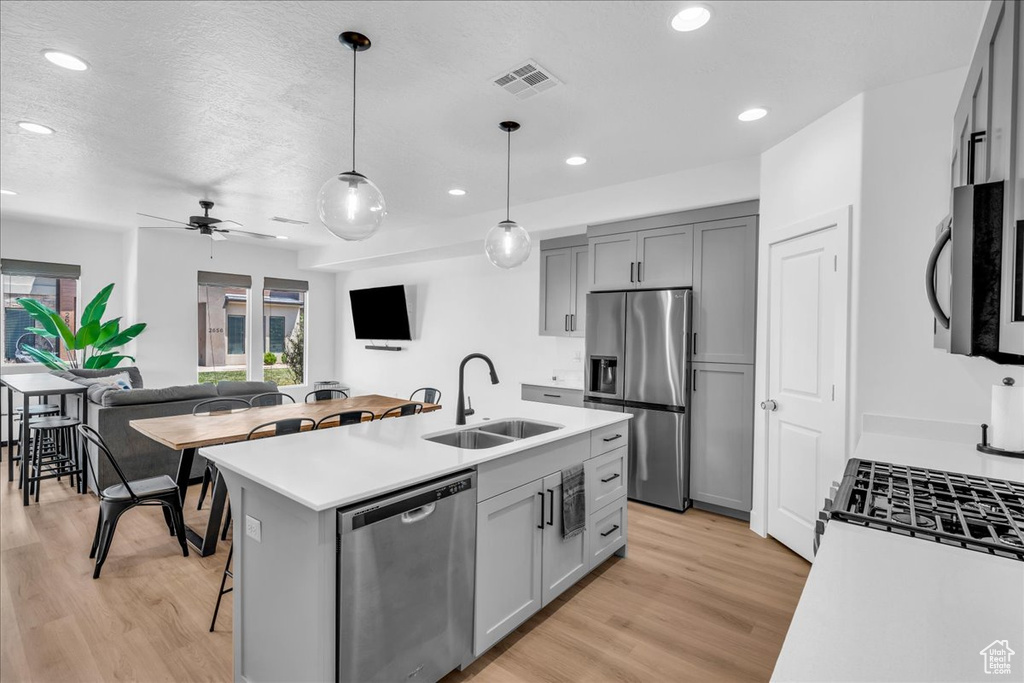Kitchen featuring appliances with stainless steel finishes, a sink, gray cabinets, light wood-style floors, and recessed lighting