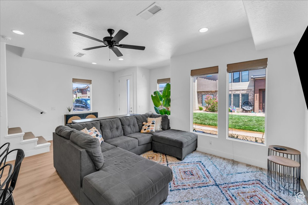 Living room with stairs, ceiling fan, recessed lighting, baseboards, and light wood-style floors