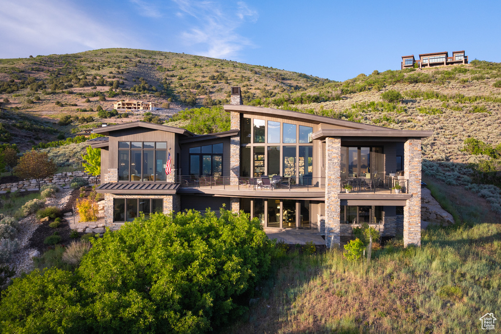 Rear view of property featuring stone siding, a chimney, and a mountain view