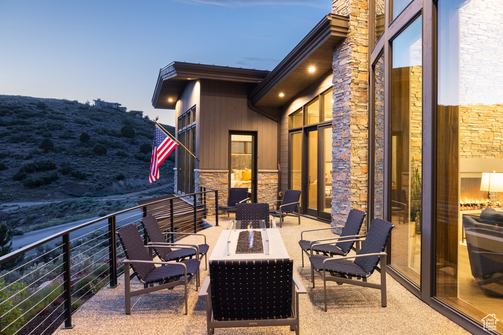 View of patio featuring an outdoor fire pit and a balcony