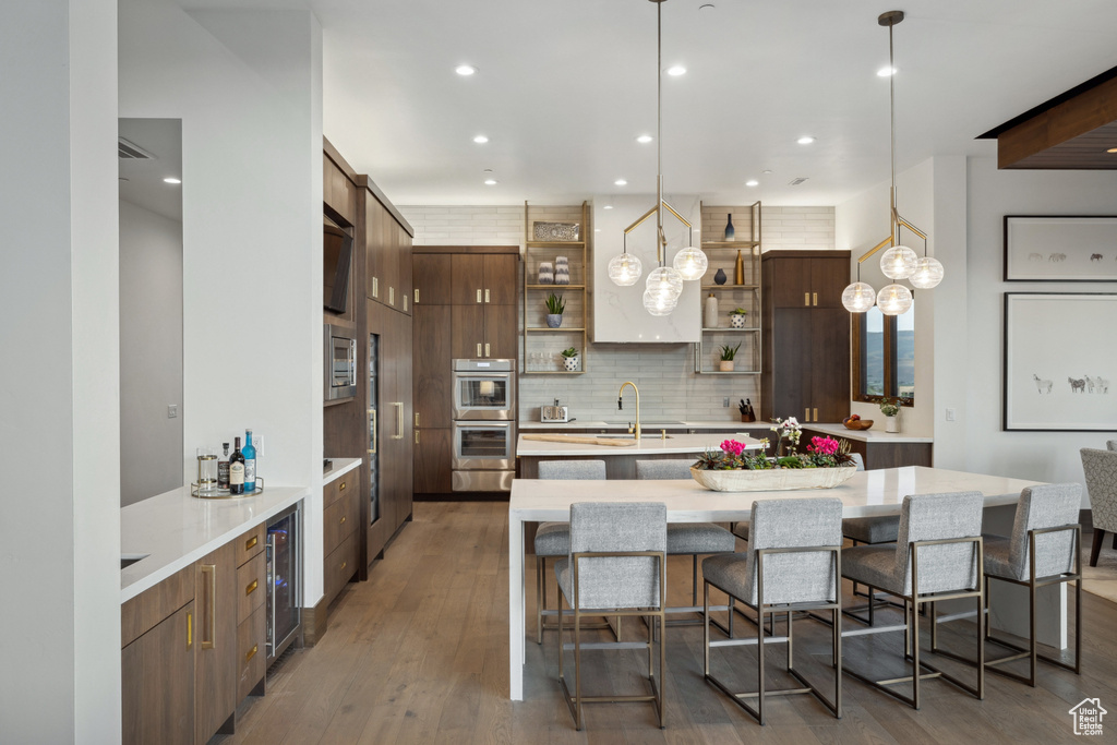 Kitchen featuring open shelves, backsplash, appliances with stainless steel finishes, light countertops, and wine cooler
