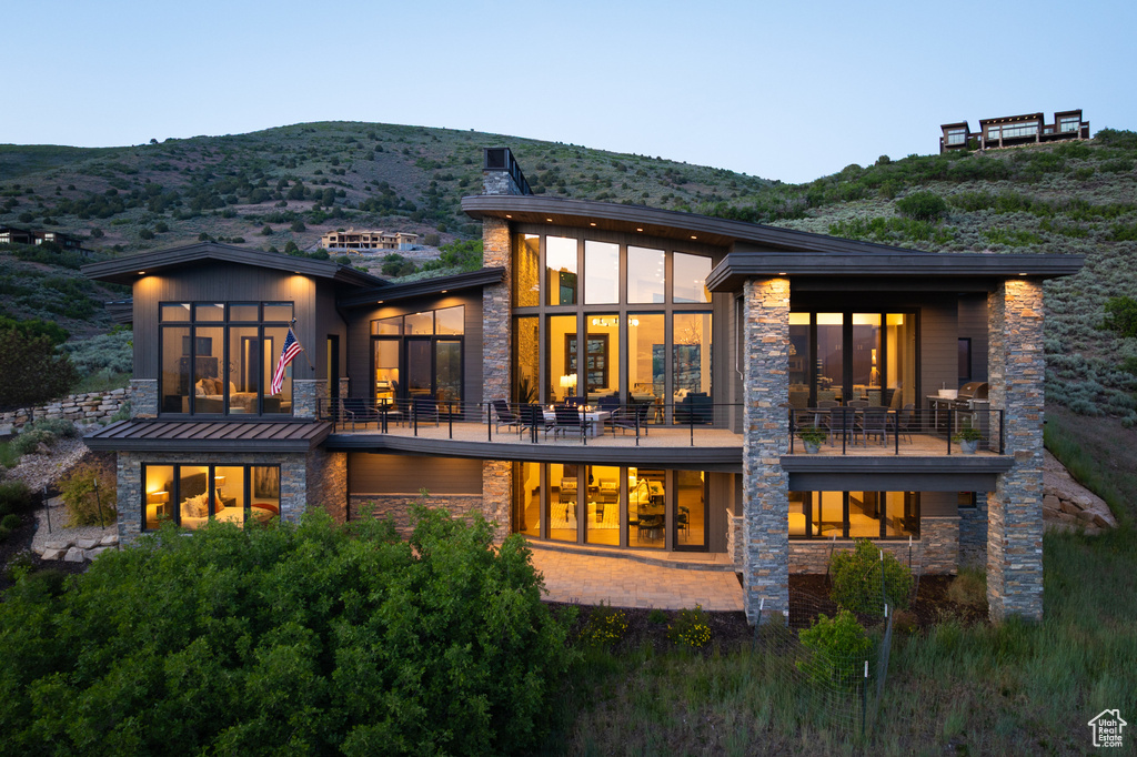Rear view of house with a balcony, stone siding, and a mountain view