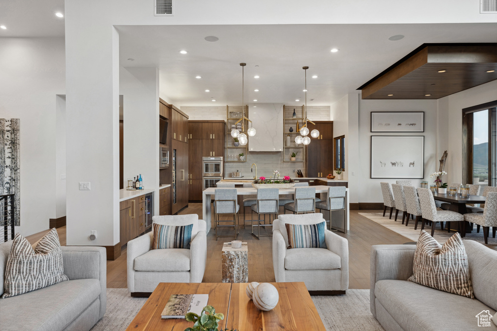 Living area featuring recessed lighting, light wood finished floors, beverage cooler, and a chandelier