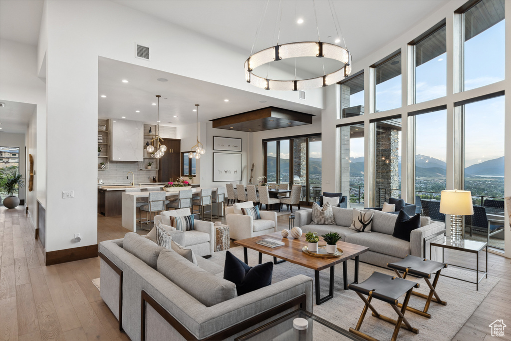 Living room with plenty of natural light, light wood finished floors, a mountain view, a high ceiling, and recessed lighting