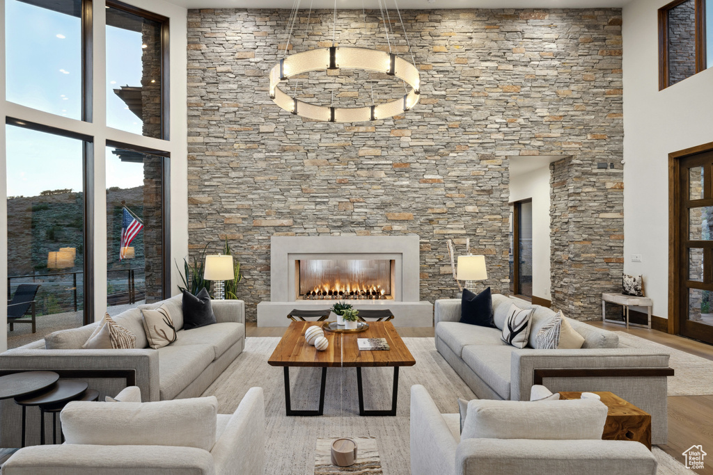 Living room with wood finished floors, a high ceiling, and a lit fireplace
