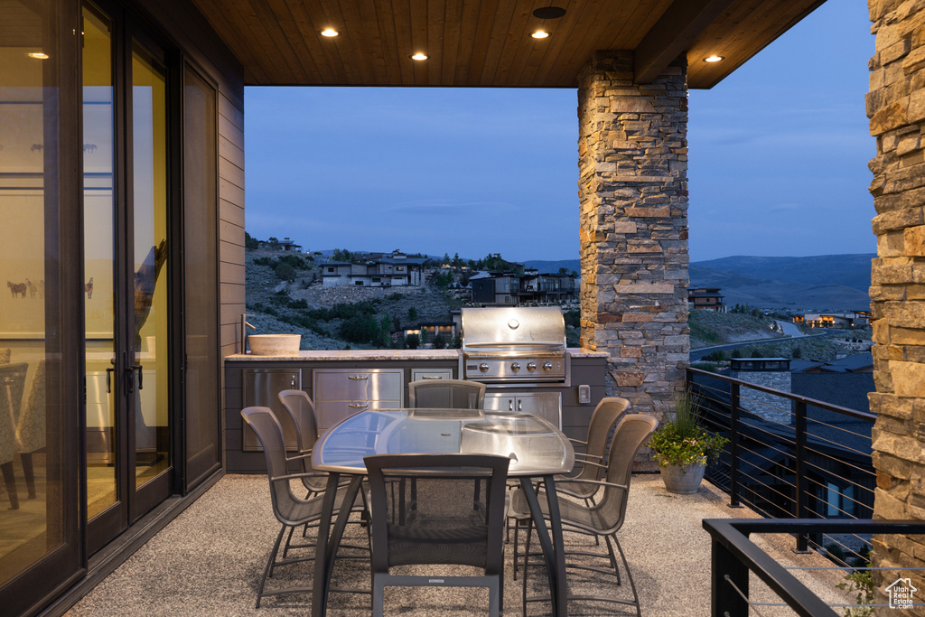 View of patio with area for grilling, a balcony, and a mountain view