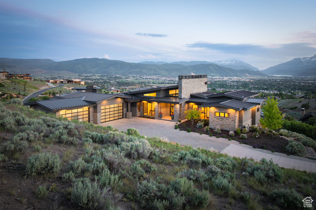 Rear view of property with a standing seam roof, a chimney, stone siding, and a mountain view
