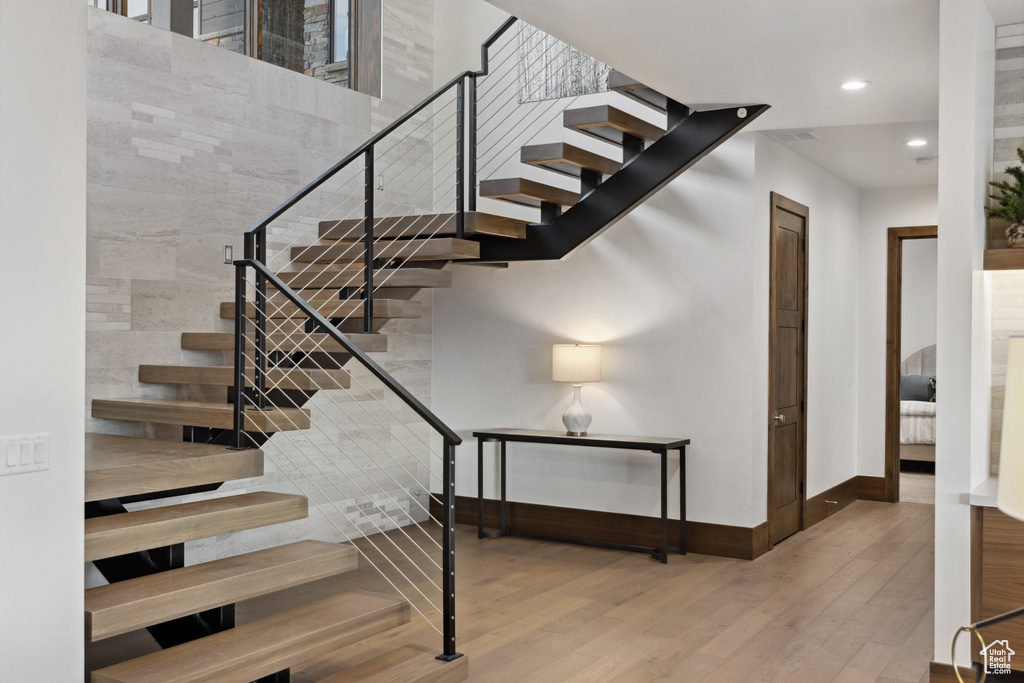 Stairway featuring wood finished floors, baseboards, and recessed lighting