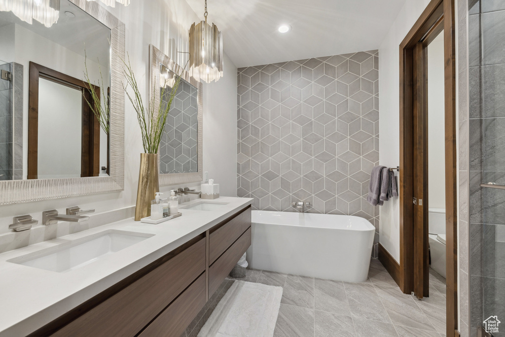 Full bath with tile walls, a soaking tub, double vanity, toilet, and recessed lighting