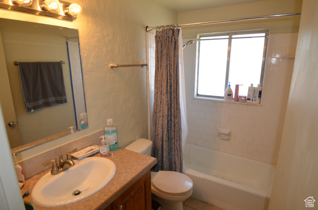 Full bath featuring a textured wall, vanity, toilet, and shower / bath combo