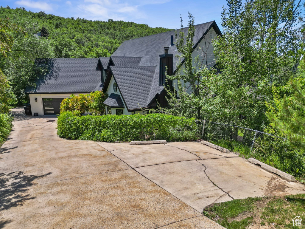 View of property exterior featuring a shingled roof and a forest view