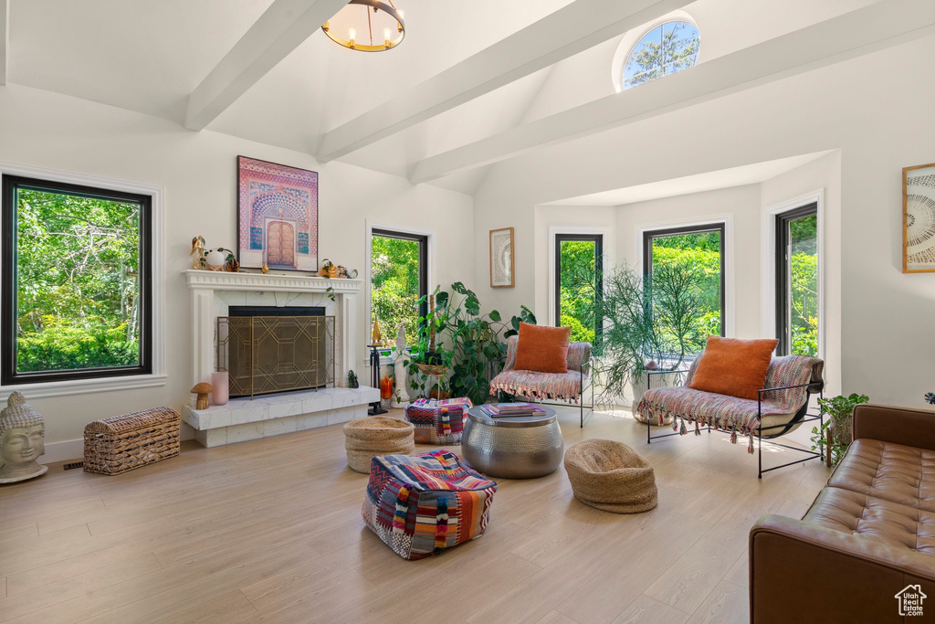 Living room featuring plenty of natural light, a fireplace, beamed ceiling, and high vaulted ceiling
